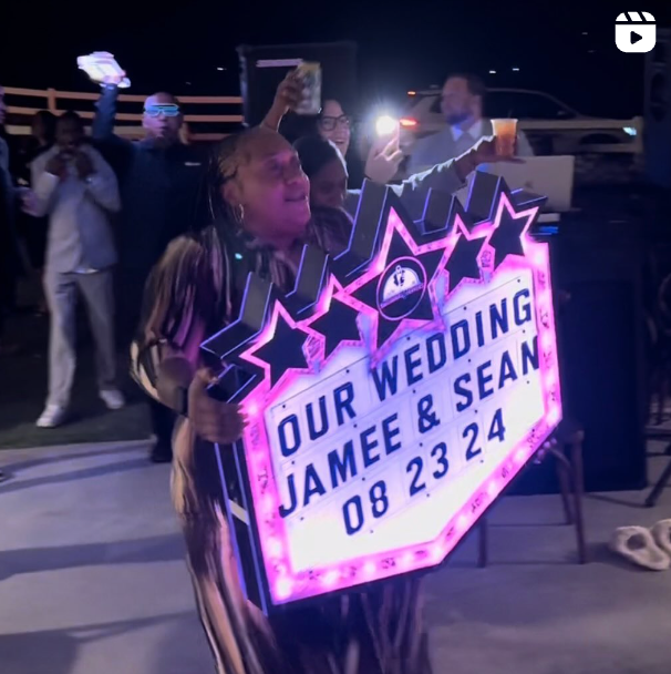 Wedding guest holding a Wedding Party Sign with a custom message.