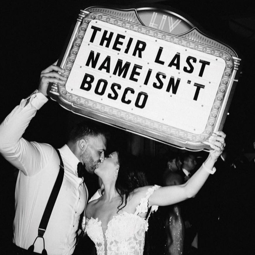 Newly married couple holding up a Wedding Party Sign with a custom message.