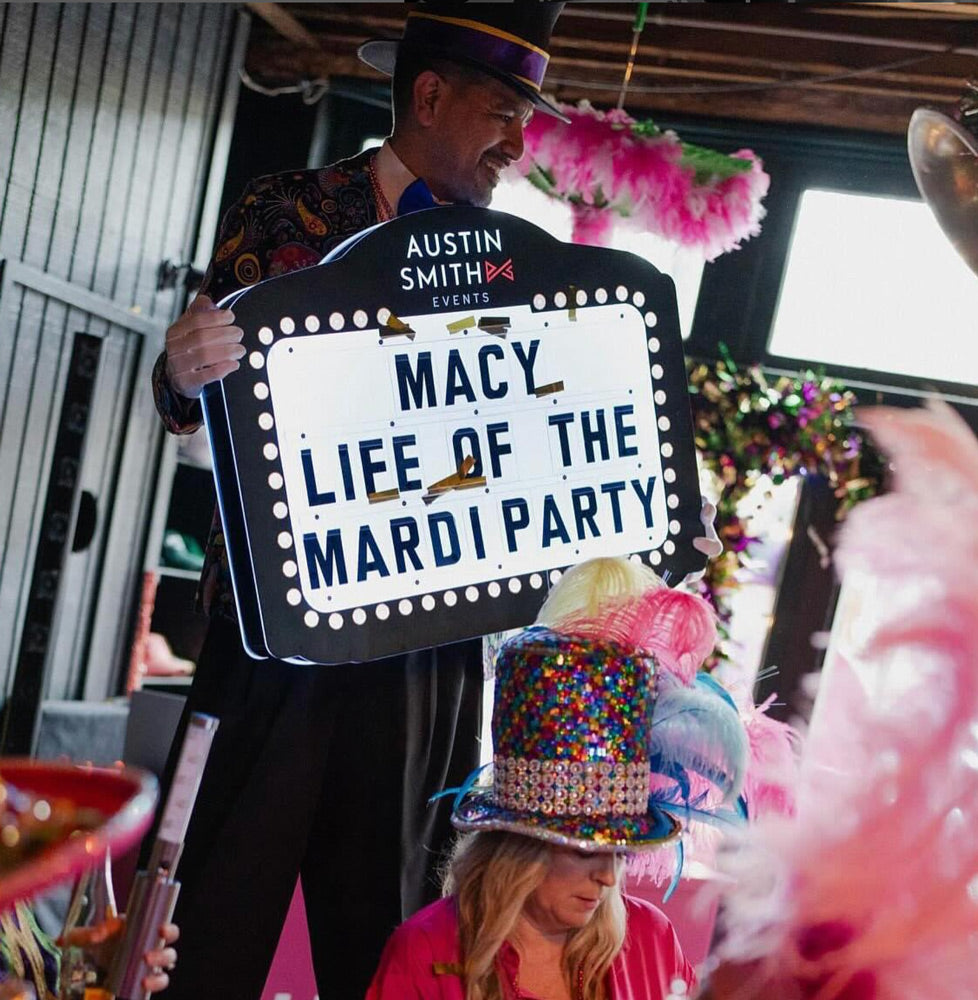Mardi Gras party guest holding a marquee sign with a custom message.