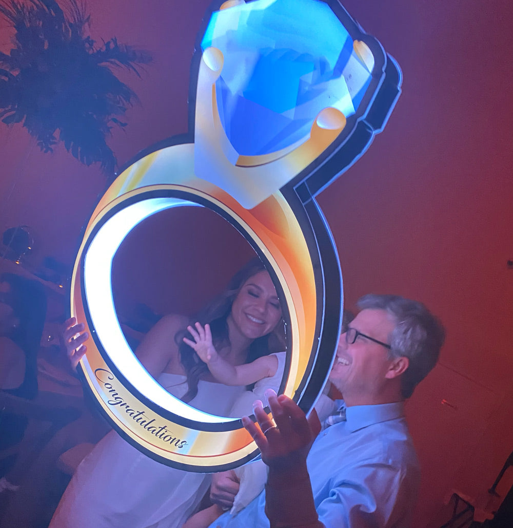 Wedding guest holding a engagement ring neon sign.