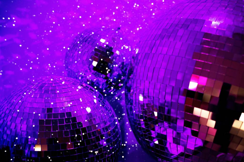 A close-up photo of disco balls under purple lights.