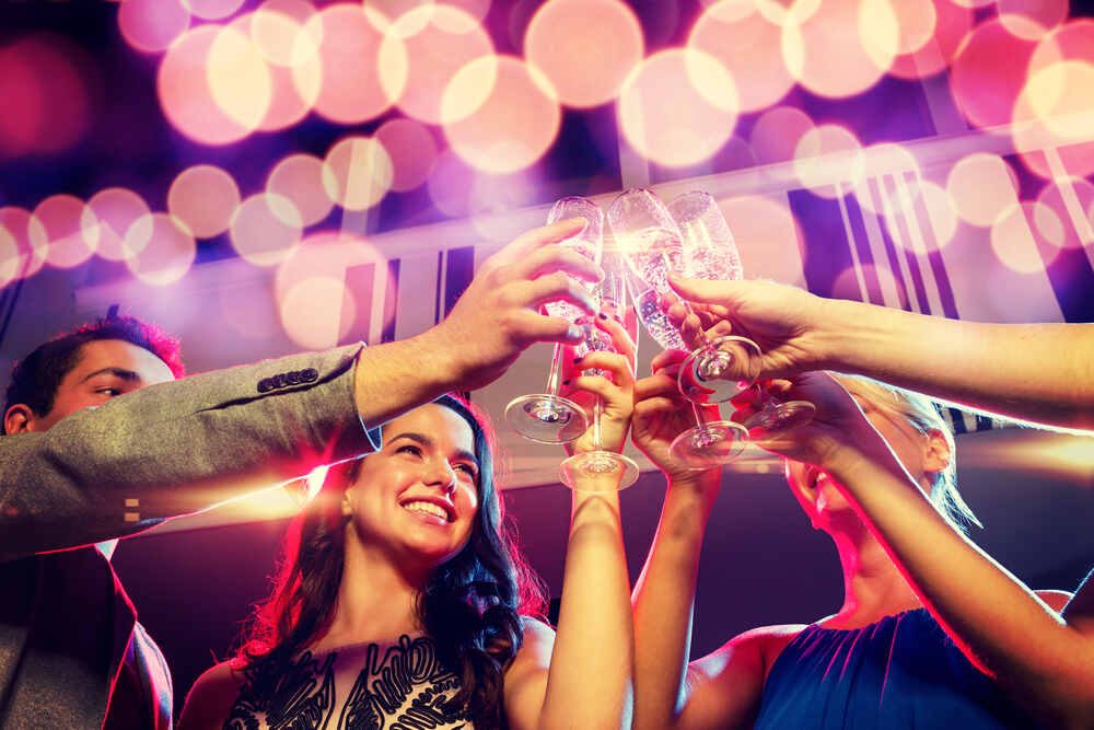 A group of friends at a VIP club experience doing a champagne cheers. 