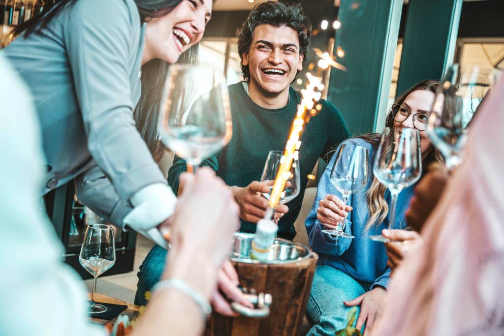A group of young people laughing at a funny bottle service sign.