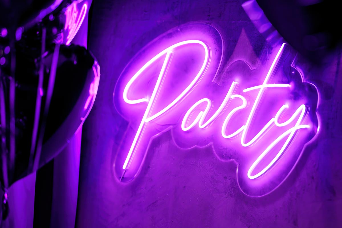 Close-up photo of a purple LED sign that says 'party' in cursive script.